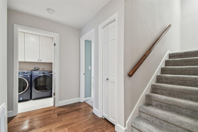 washroom featuring cabinets, washing machine and dryer, and hardwood / wood-style floors