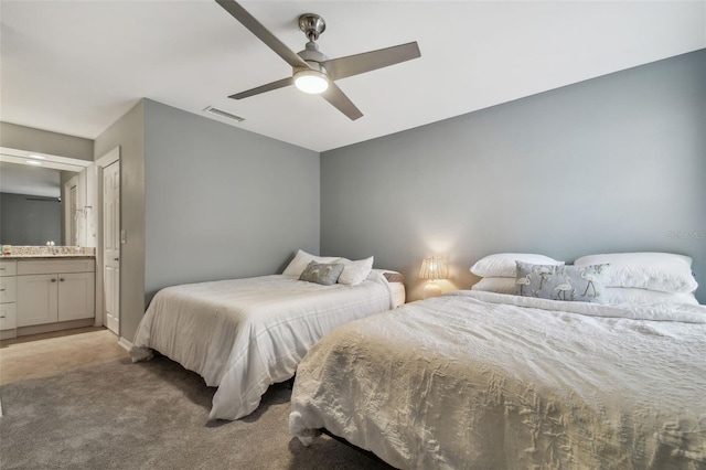 bedroom featuring ceiling fan, ensuite bathroom, and light colored carpet