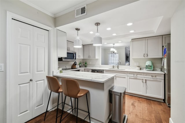 kitchen featuring kitchen peninsula, decorative light fixtures, sink, a kitchen bar, and crown molding