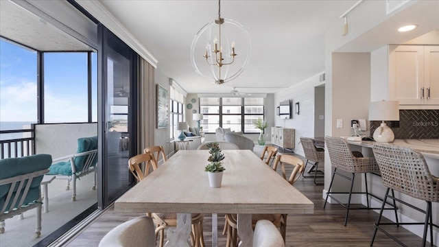 dining room with dark hardwood / wood-style flooring, a notable chandelier, a healthy amount of sunlight, and a water view