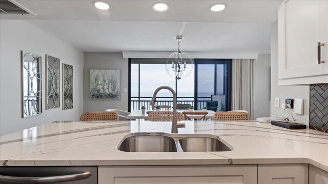 kitchen with sink, dishwasher, light stone countertops, decorative backsplash, and white cabinets