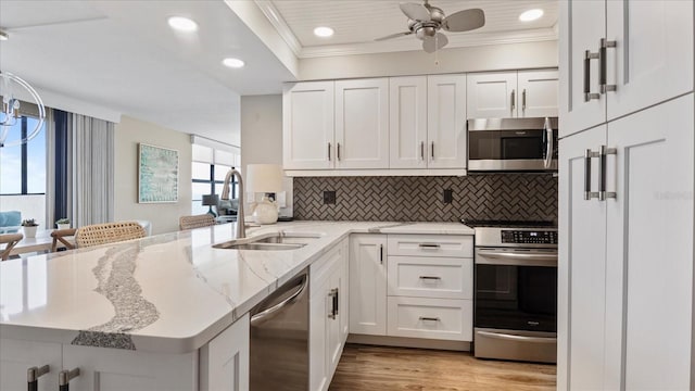 kitchen with white cabinetry, appliances with stainless steel finishes, kitchen peninsula, and sink