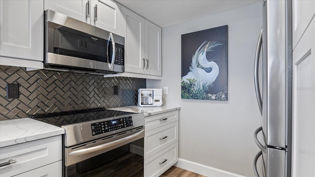 kitchen featuring tasteful backsplash, white cabinetry, light hardwood / wood-style floors, stainless steel appliances, and light stone countertops