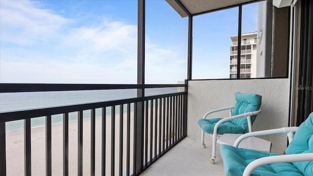 sunroom with a water view and a beach view