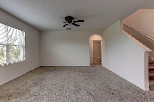 empty room featuring a textured ceiling, light colored carpet, and ceiling fan