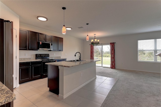 kitchen featuring decorative light fixtures, an island with sink, sink, stainless steel appliances, and light carpet