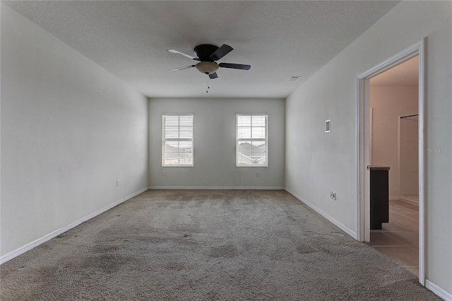 spare room featuring light carpet, a textured ceiling, and ceiling fan