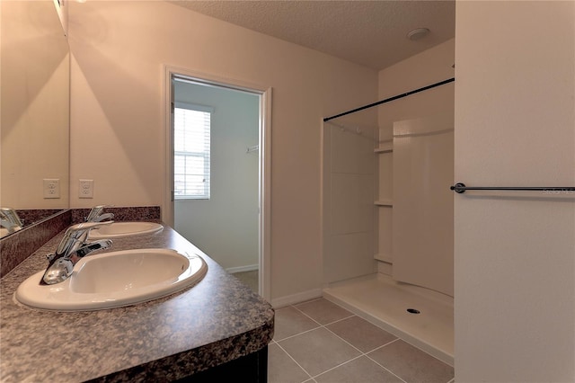 bathroom with walk in shower, tile patterned floors, vanity, and a textured ceiling