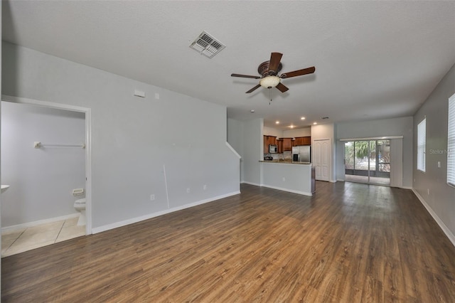 unfurnished living room with ceiling fan, dark hardwood / wood-style floors, and a textured ceiling