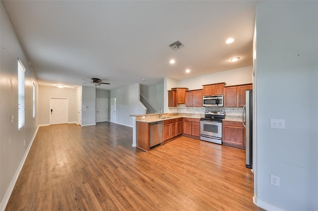 kitchen featuring appliances with stainless steel finishes, sink, ceiling fan, kitchen peninsula, and light wood-type flooring