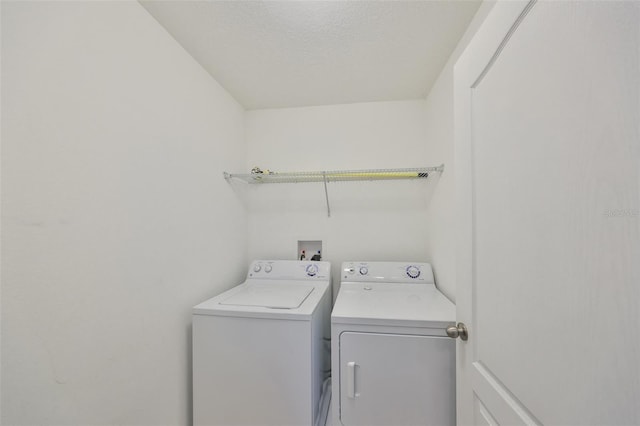 laundry room featuring washing machine and clothes dryer and a textured ceiling