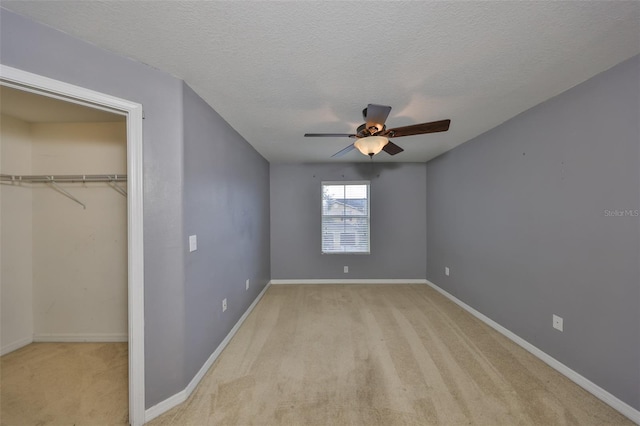 unfurnished bedroom with ceiling fan, light colored carpet, a closet, and a textured ceiling