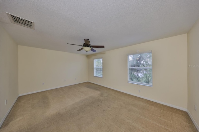 carpeted empty room with ceiling fan and a textured ceiling