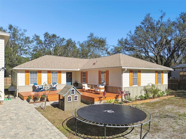 back of property featuring a trampoline and a wooden deck