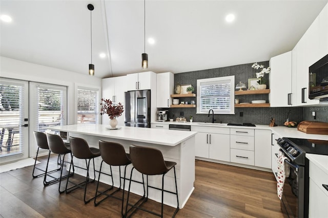 kitchen featuring a kitchen island, pendant lighting, white cabinetry, sink, and black appliances