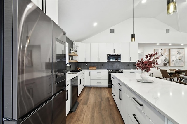 kitchen with decorative light fixtures, white cabinetry, lofted ceiling, sink, and stainless steel appliances