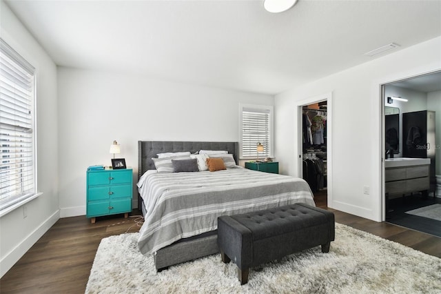 bedroom featuring multiple windows, a spacious closet, dark hardwood / wood-style flooring, and a closet