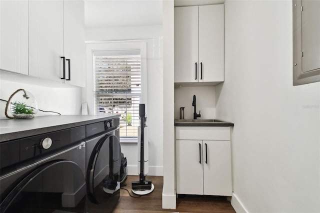 laundry area featuring dark wood-type flooring, cabinets, washer and clothes dryer, and sink