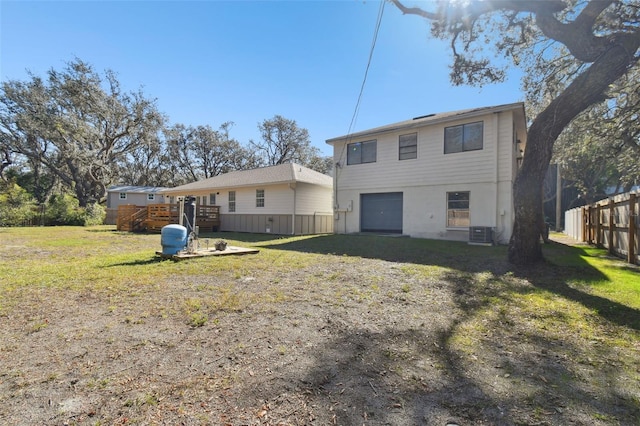 back of house featuring a garage, central AC, a deck, and a lawn