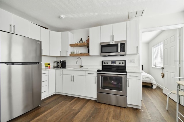 kitchen with sink, a textured ceiling, stainless steel appliances, and white cabinets