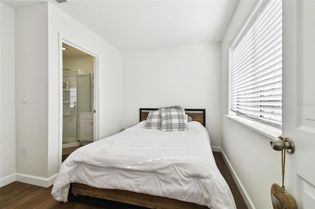 bedroom with multiple windows, ensuite bath, and dark wood-type flooring