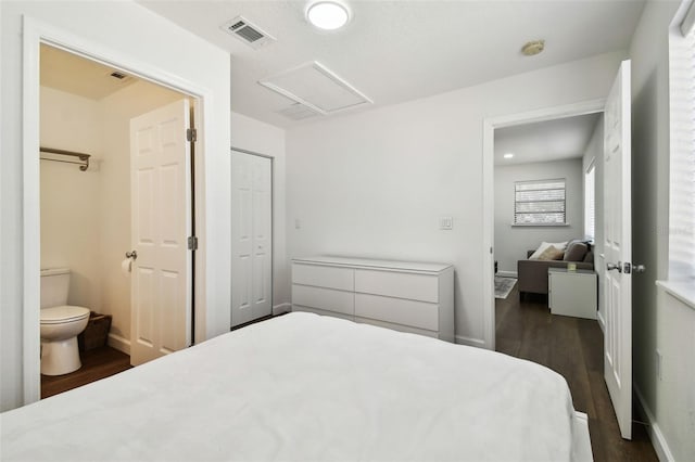 bedroom with ensuite bathroom and dark hardwood / wood-style floors