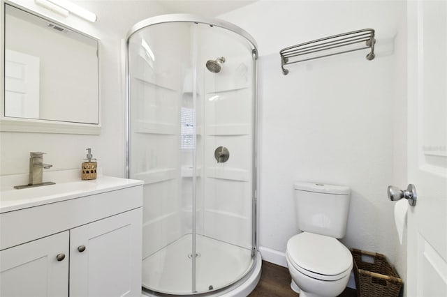 bathroom with hardwood / wood-style flooring, toilet, vanity, and a shower with shower door