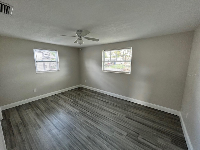 empty room featuring dark hardwood / wood-style floors, a wealth of natural light, and ceiling fan