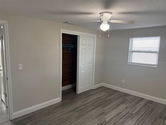 unfurnished bedroom with ceiling fan, a closet, a textured ceiling, and dark hardwood / wood-style floors