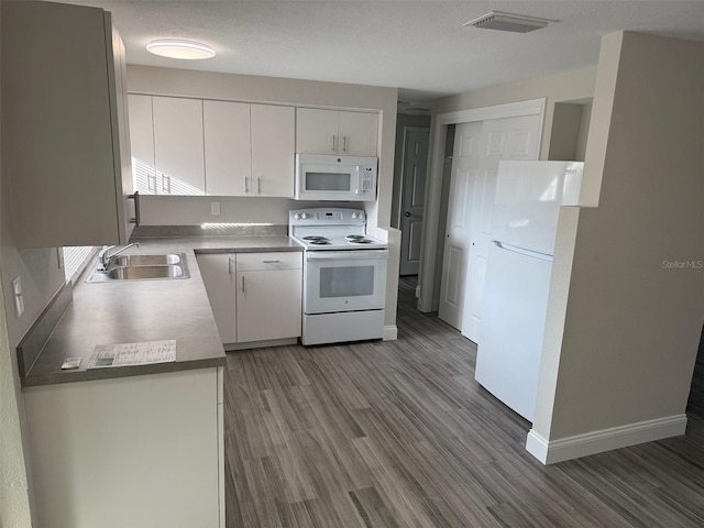 kitchen featuring white appliances, wood-type flooring, white cabinetry, and sink