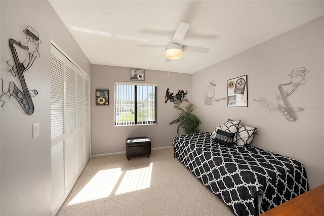 carpeted bedroom featuring ceiling fan, a closet, and a textured ceiling