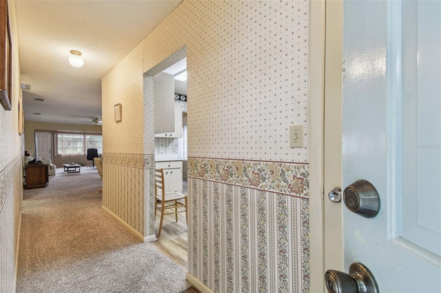 hallway with light carpet and a textured ceiling