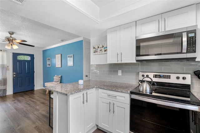 kitchen featuring white cabinetry, tasteful backsplash, dark hardwood / wood-style floors, stainless steel appliances, and light stone countertops