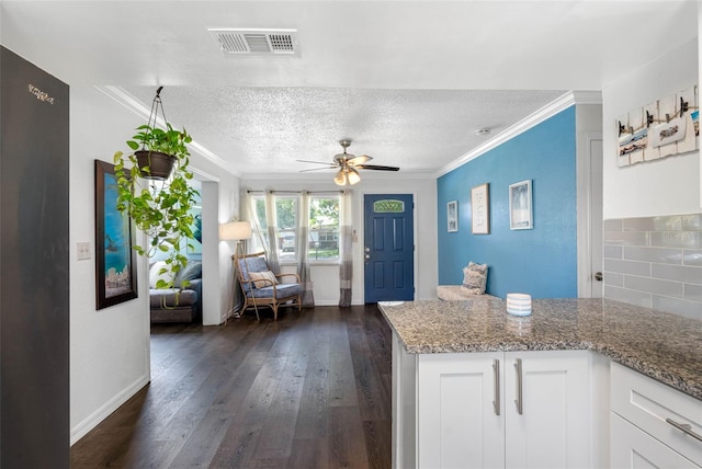 kitchen with white cabinetry, ornamental molding, and light stone counters