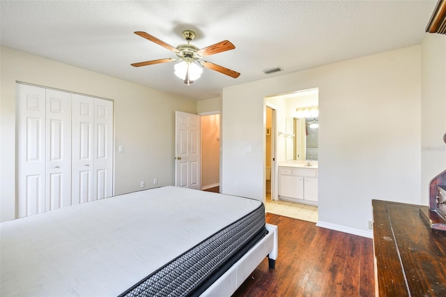 bedroom featuring ceiling fan, dark hardwood / wood-style floors, connected bathroom, a textured ceiling, and a closet