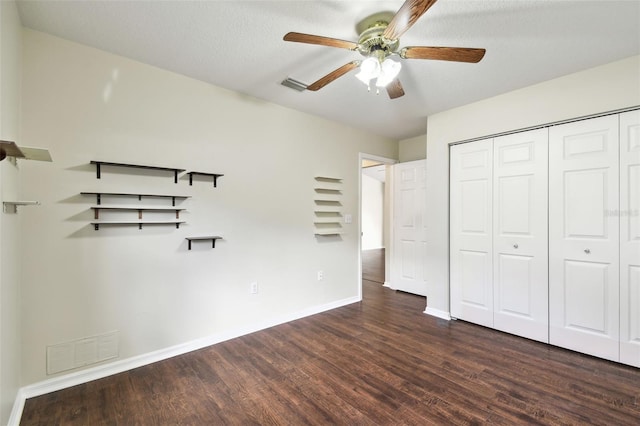 unfurnished bedroom with dark wood-type flooring, ceiling fan, a closet, and a textured ceiling