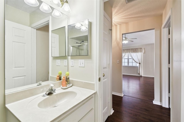 bathroom featuring hardwood / wood-style flooring, ceiling fan, vanity, and a textured ceiling