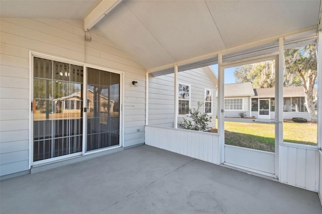 unfurnished sunroom featuring lofted ceiling with beams and a wealth of natural light