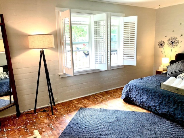 bedroom with brick wall and hardwood / wood-style floors