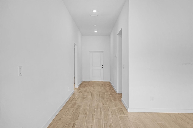 corridor featuring baseboards, light wood-style floors, and recessed lighting