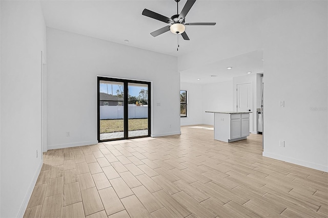 unfurnished living room with baseboards, a ceiling fan, and wood finish floors