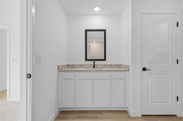 bathroom featuring wood finished floors, baseboards, and vanity