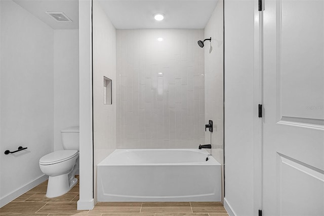 bathroom featuring toilet, wood finish floors, visible vents, washtub / shower combination, and baseboards