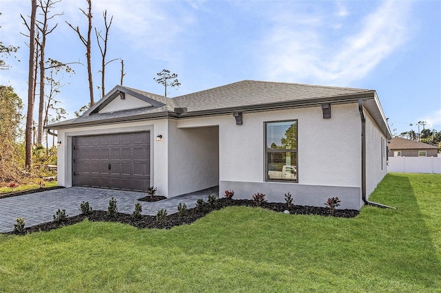 ranch-style house with a garage, stucco siding, fence, a front lawn, and decorative driveway