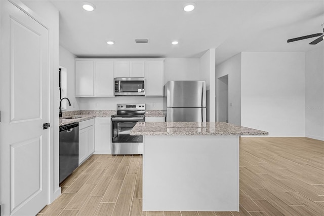 kitchen with a center island, light wood-style flooring, a sink, visible vents, and appliances with stainless steel finishes