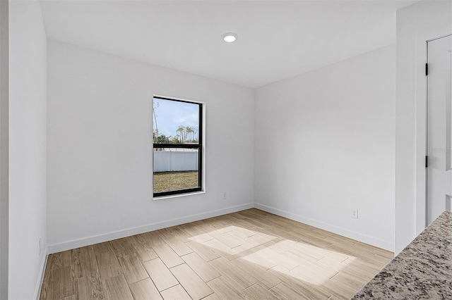 empty room with light wood-style flooring, baseboards, and recessed lighting