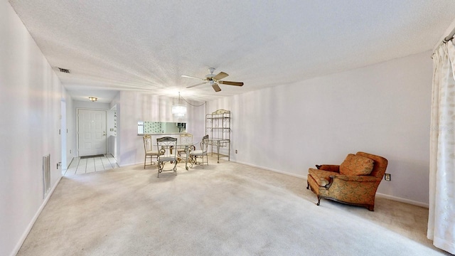 interior space with ceiling fan, light colored carpet, and a textured ceiling