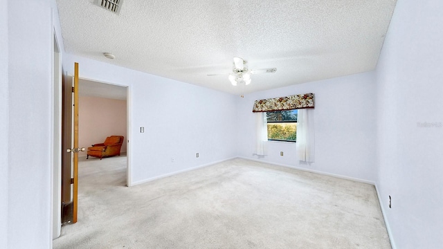 empty room featuring light colored carpet, a textured ceiling, and ceiling fan