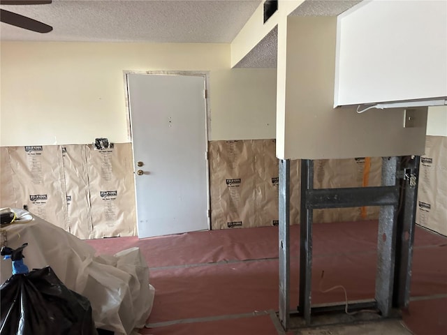 miscellaneous room with ceiling fan and a textured ceiling