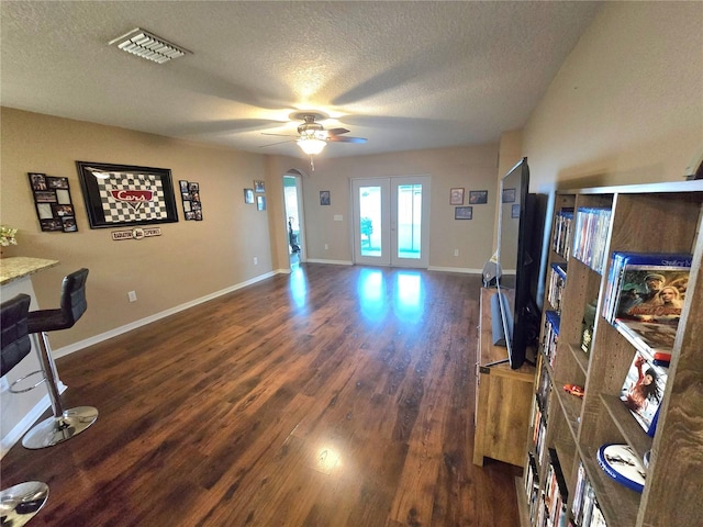 living area with french doors, dark wood finished floors, visible vents, a textured ceiling, and baseboards